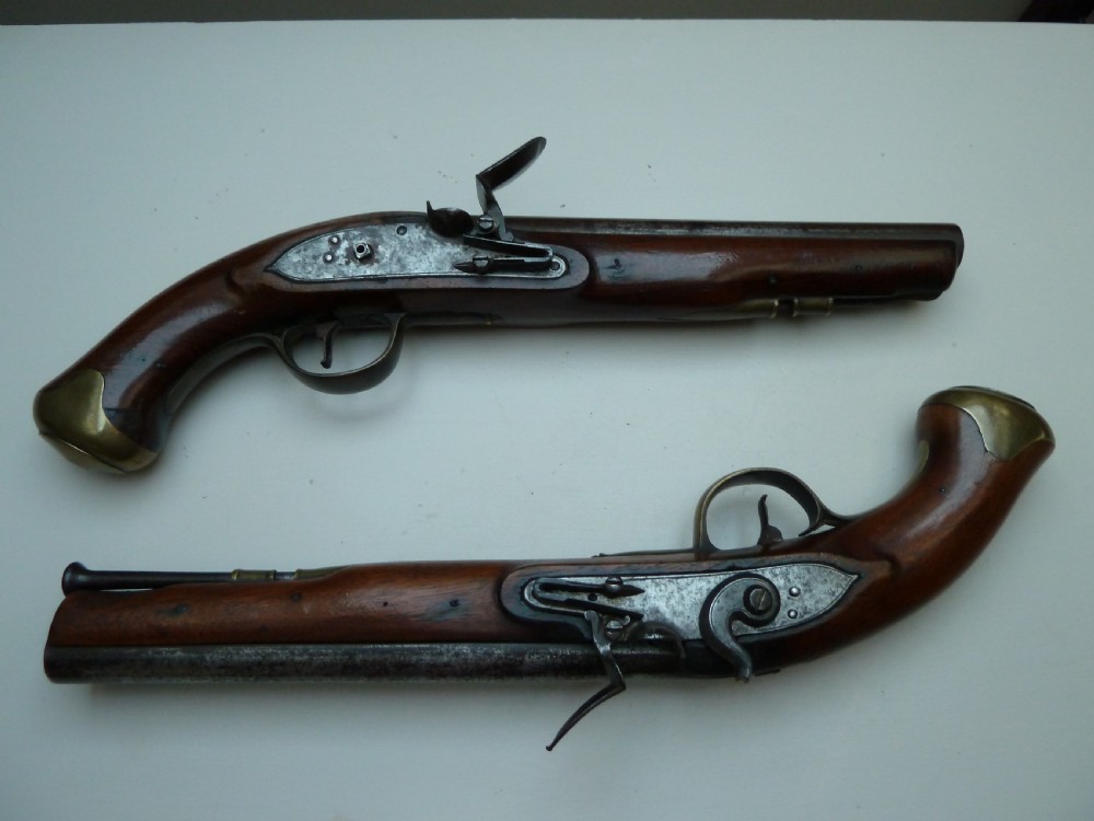 A pair of early 19th-century flintlock duelling pistols featuring contoured wooden stocks, brass sideplates, and steel barrels. View XIV