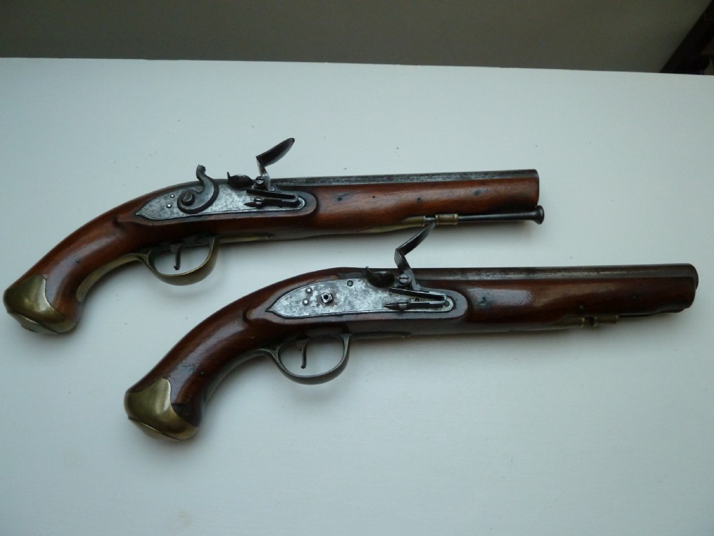 A pair of early 19th-century flintlock duelling pistols featuring contoured wooden stocks, brass sideplates, and steel barrels. View XV