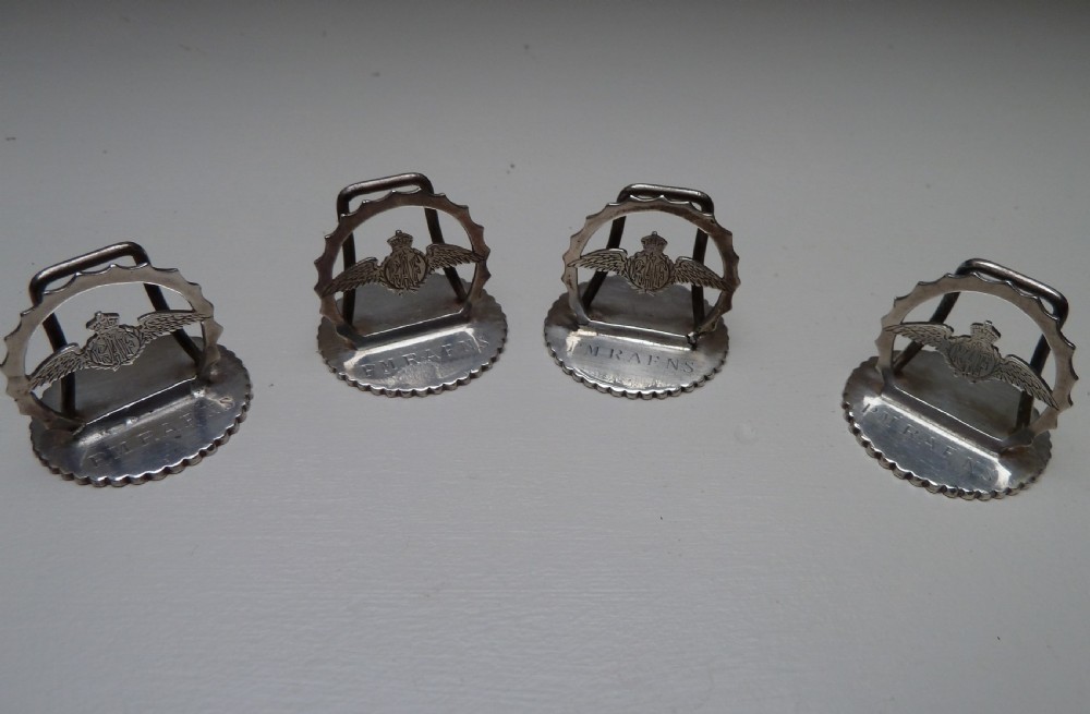 Set of four silver RAF menu holders featuring Royal Air Force wings and crown motifs on scalloped circular bases.