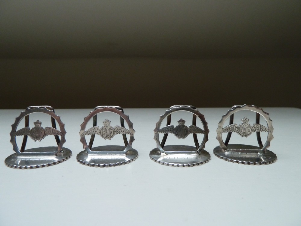Set of four silver RAF menu holders featuring Royal Air Force wings and crown motifs on scalloped circular bases. View II