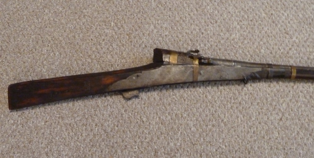 An antique Indian matchlock Torador musket featuring a long steel barrel bound with brass straps to a dark wood stock. View II