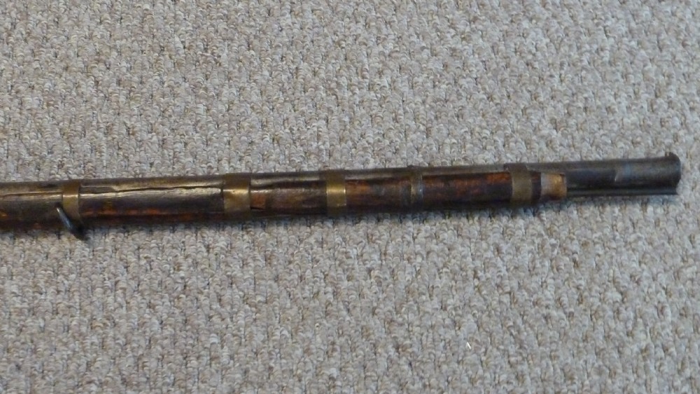 An antique Indian matchlock Torador musket featuring a long steel barrel bound with brass straps to a dark wood stock. View IV
