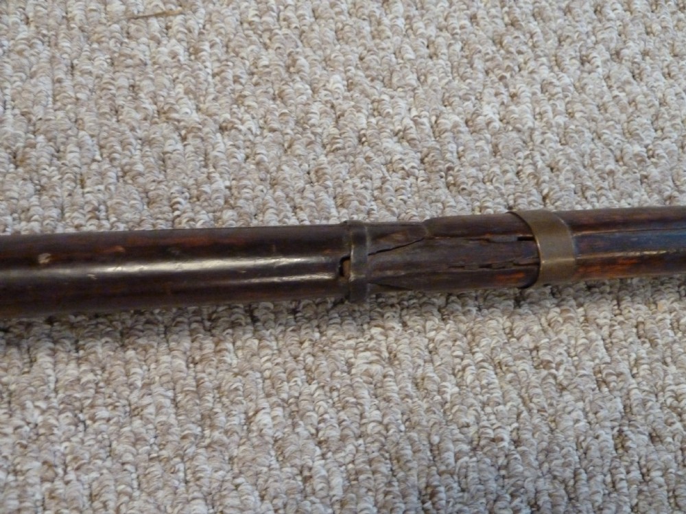An antique Indian matchlock Torador musket featuring a long steel barrel bound with brass straps to a dark wood stock. View XI
