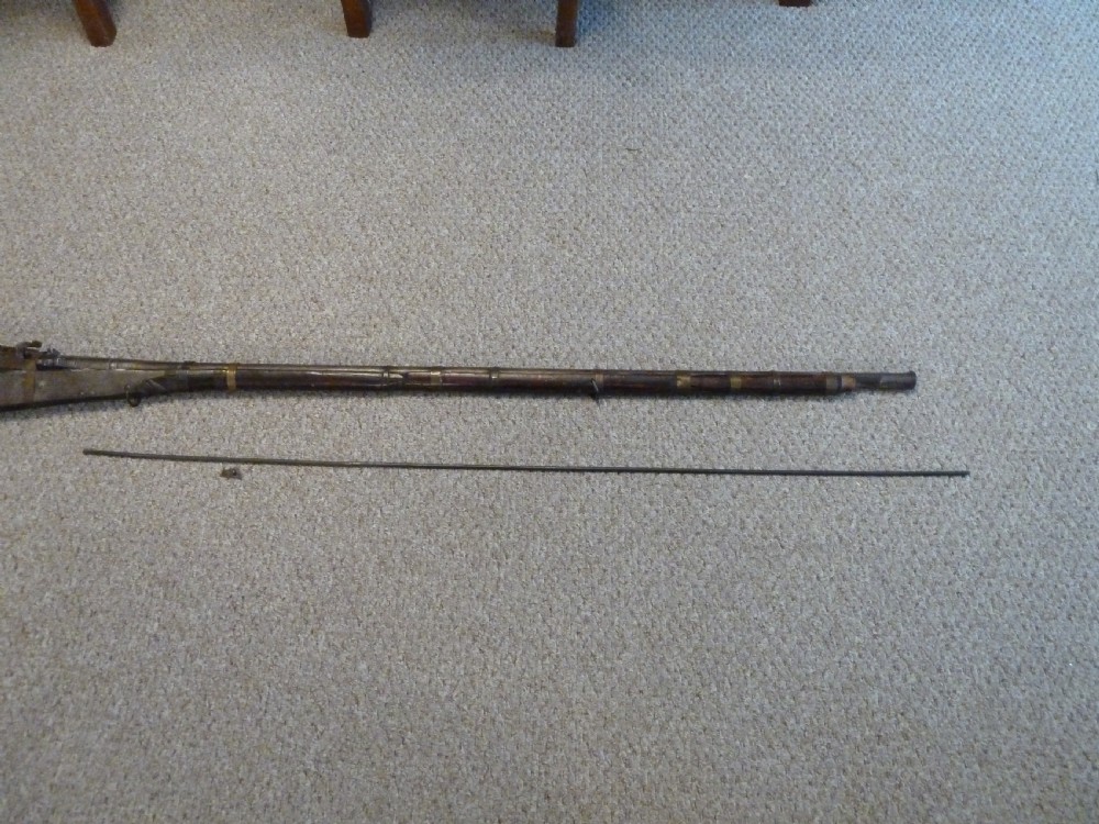 An antique Indian matchlock Torador musket featuring a long steel barrel bound with brass straps to a dark wood stock. View XIII