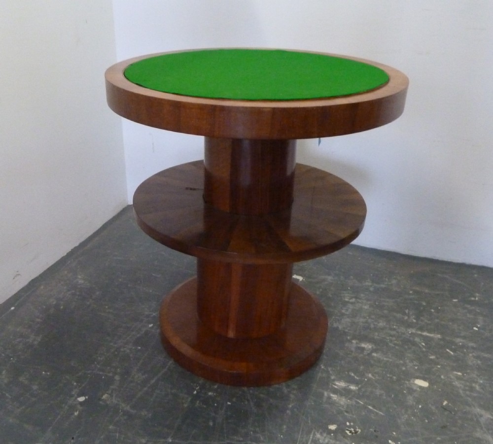 A circular Art Deco walnut metamorphic card table featuring a quarter-veneered top, central cylindrical column, and tiered circular shelf. View III
