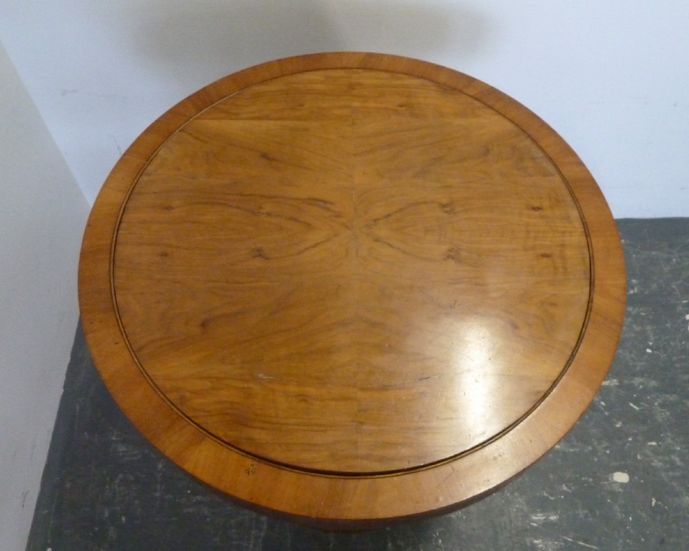 A circular Art Deco walnut metamorphic card table featuring a quarter-veneered top, central cylindrical column, and tiered circular shelf. View X