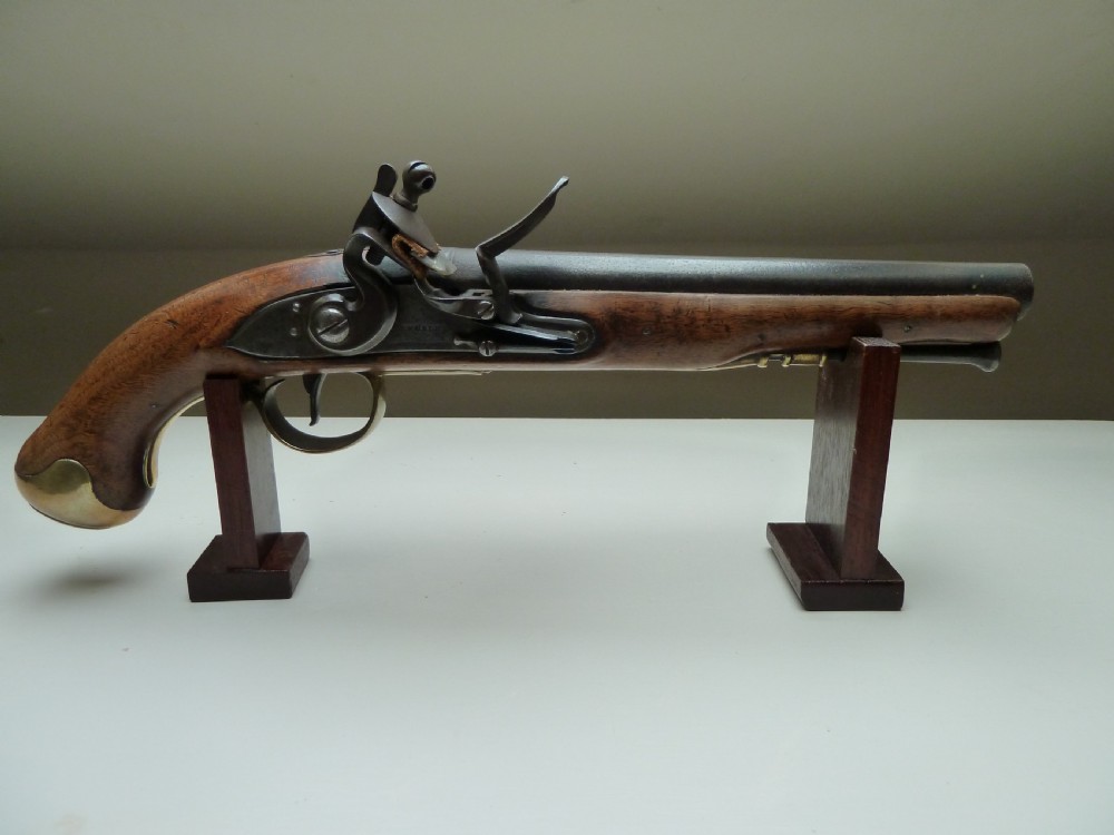 An 18th-century flintlock pistol featuring a carved dark walnut stock, a steel barrel and flint mechanism, and a brass butt cap.