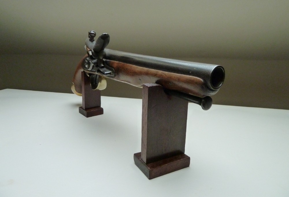 An 18th-century flintlock pistol featuring a carved dark walnut stock, a steel barrel and flint mechanism, and a brass butt cap. View IV