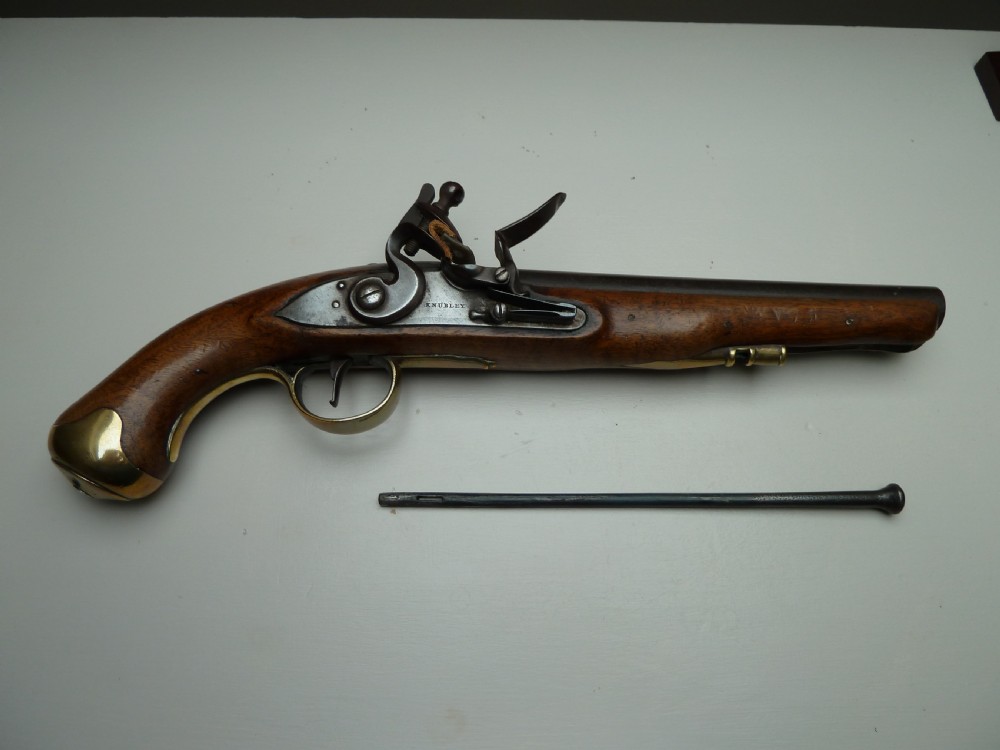 An 18th-century flintlock pistol featuring a carved dark walnut stock, a steel barrel and flint mechanism, and a brass butt cap. View VI