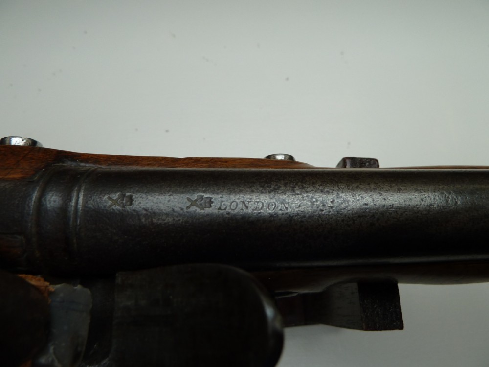 An 18th-century flintlock pistol featuring a carved dark walnut stock, a steel barrel and flint mechanism, and a brass butt cap. View IX