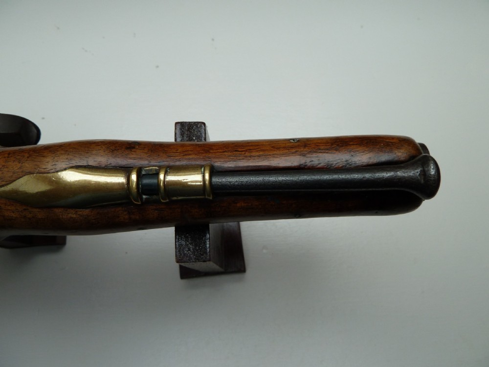 An 18th-century flintlock pistol featuring a carved dark walnut stock, a steel barrel and flint mechanism, and a brass butt cap. View XII