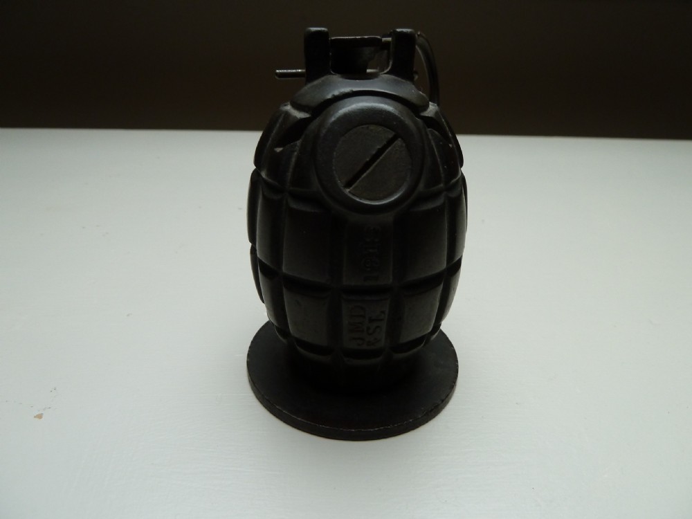 A dark cast iron money box shaped like a First World War hand grenade with a top pull ring and coin slot. View II
