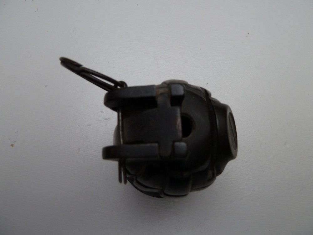 A dark cast iron money box shaped like a First World War hand grenade with a top pull ring and coin slot. View V