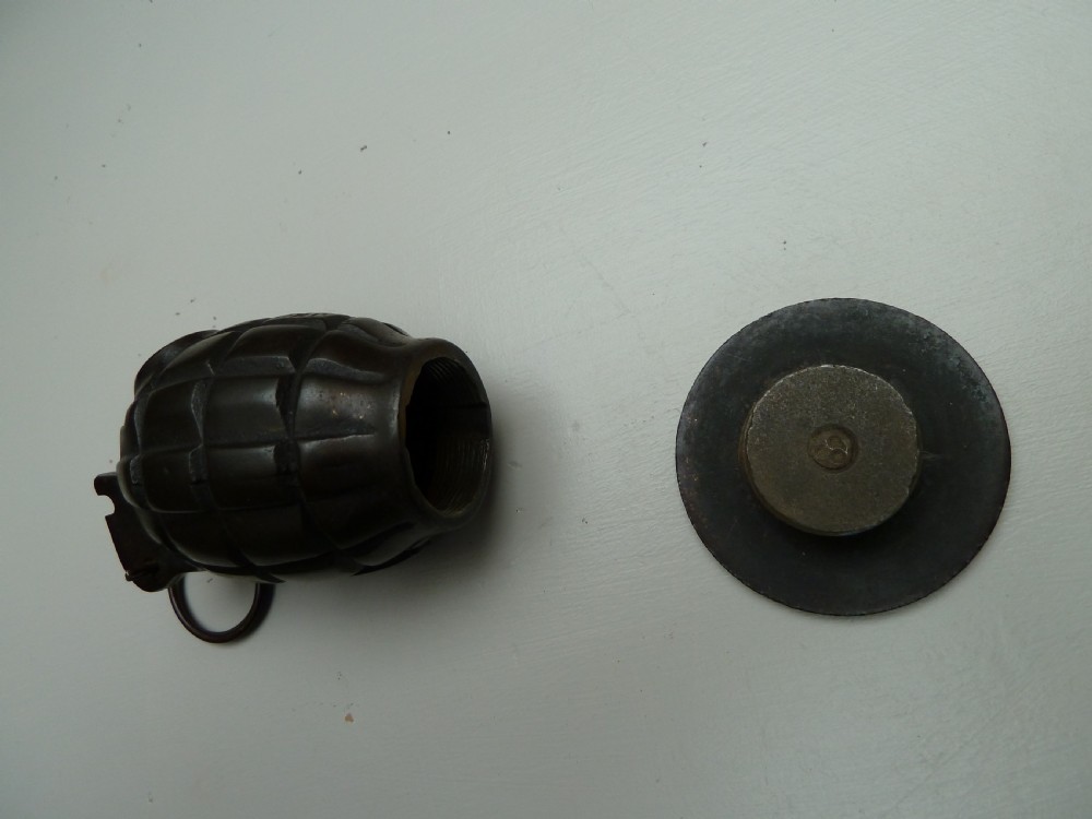 A dark cast iron money box shaped like a First World War hand grenade with a top pull ring and coin slot. View VI