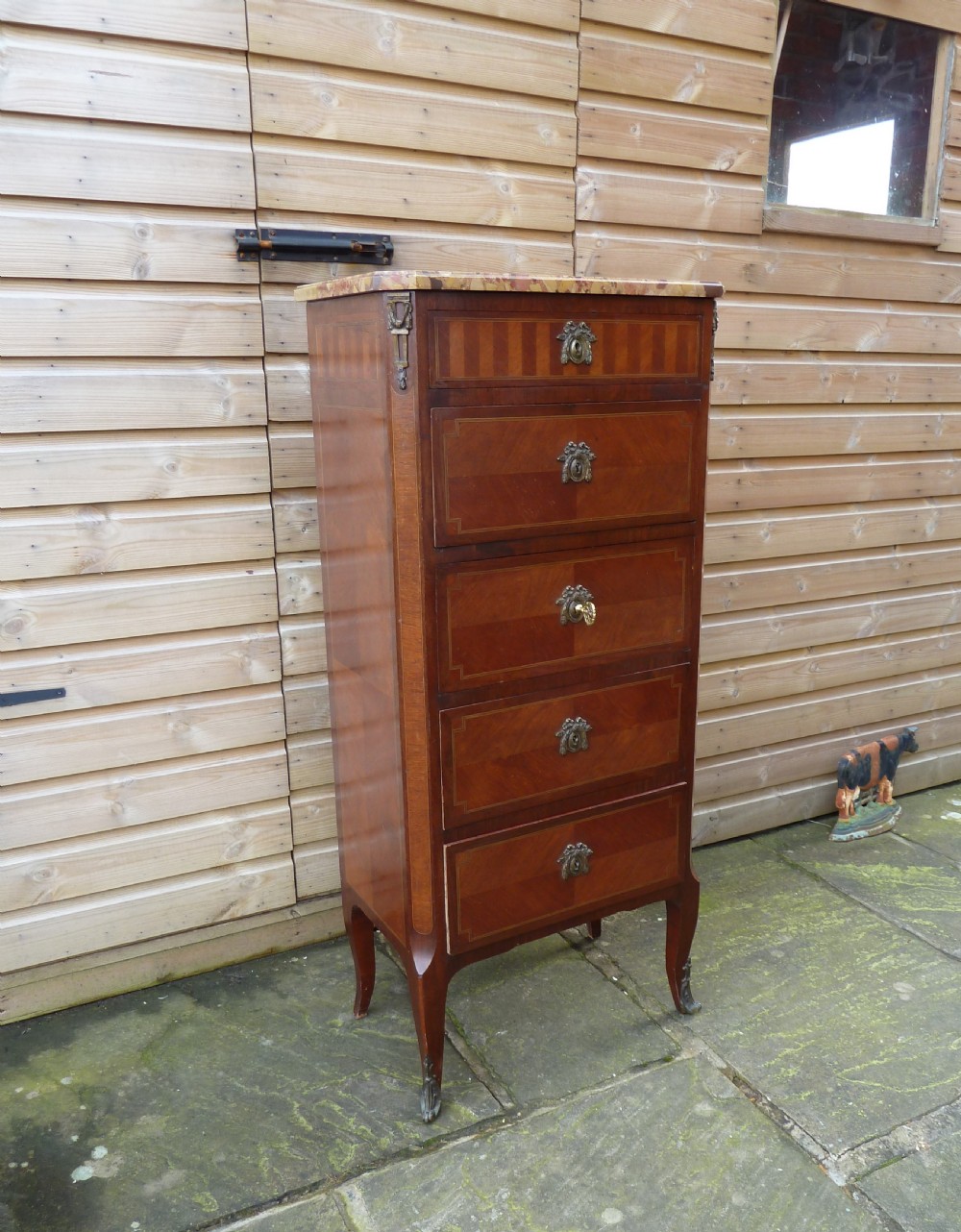 A tall French semainier chest of drawers featuring five inlaid timber drawers, bronze escutcheons, cabriole legs, and a marble top.