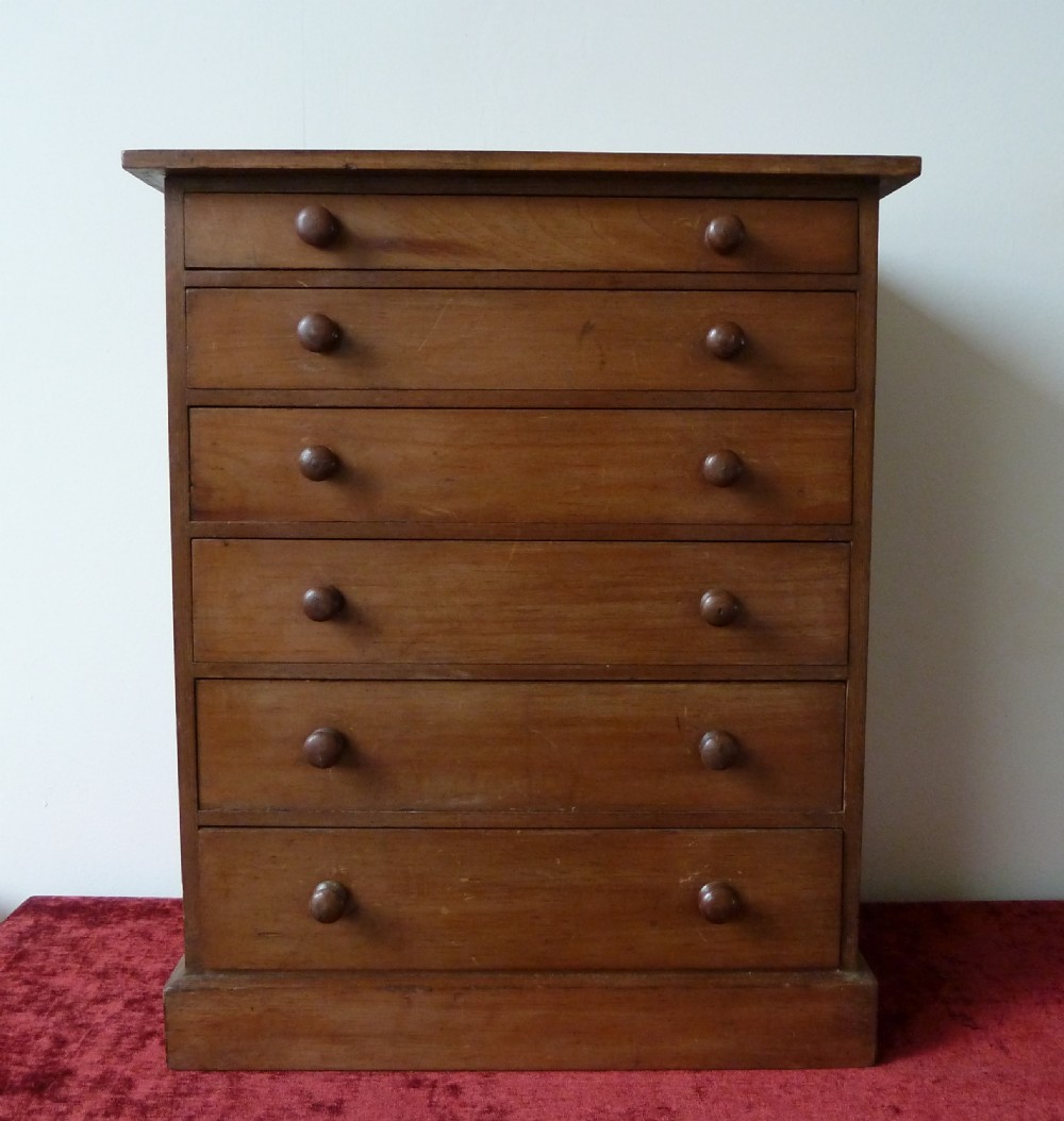 A Victorian pine chest featuring six shallow drawers with turned wooden knobs and a solid plinth base.