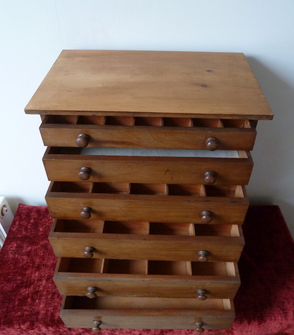 A Victorian pine chest featuring six shallow drawers with turned wooden knobs and a solid plinth base. View VIII