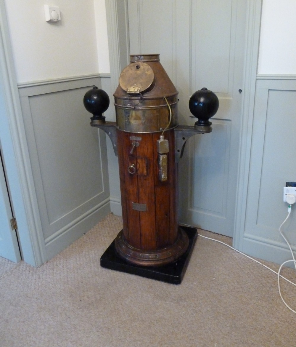 A 19th-century floor-standing ships binnacle featuring a polished brass hood with a glass viewing window, a wooden cylindrical pedestal, and two black iron spheres mounted on side brackets. View III