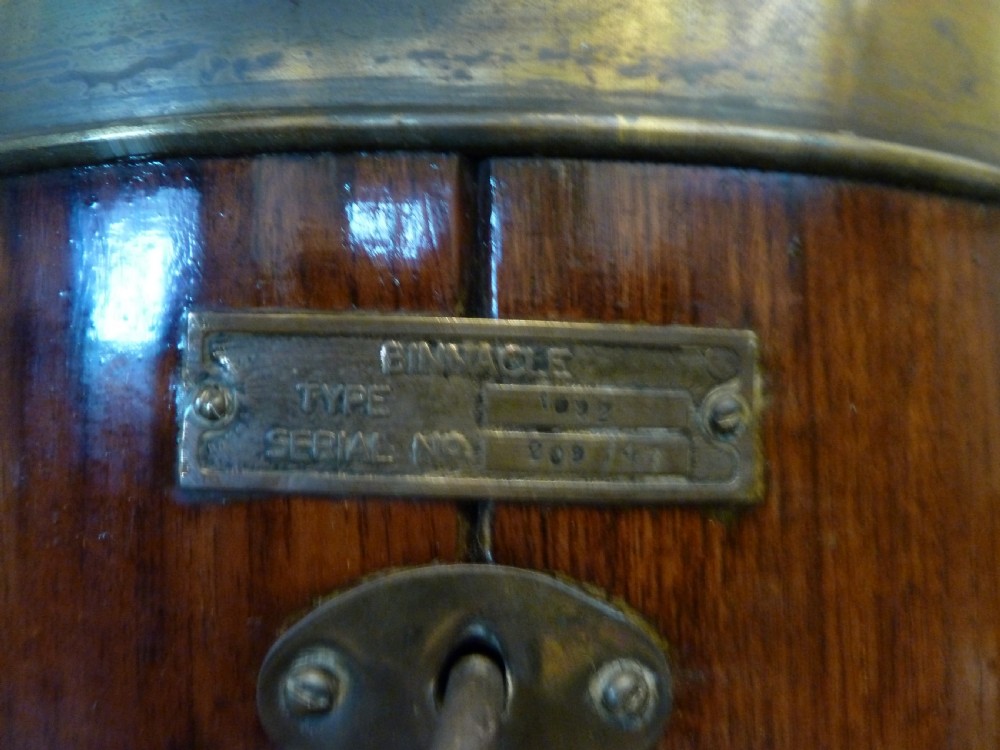 A 19th-century floor-standing ships binnacle featuring a polished brass hood with a glass viewing window, a wooden cylindrical pedestal, and two black iron spheres mounted on side brackets. View X
