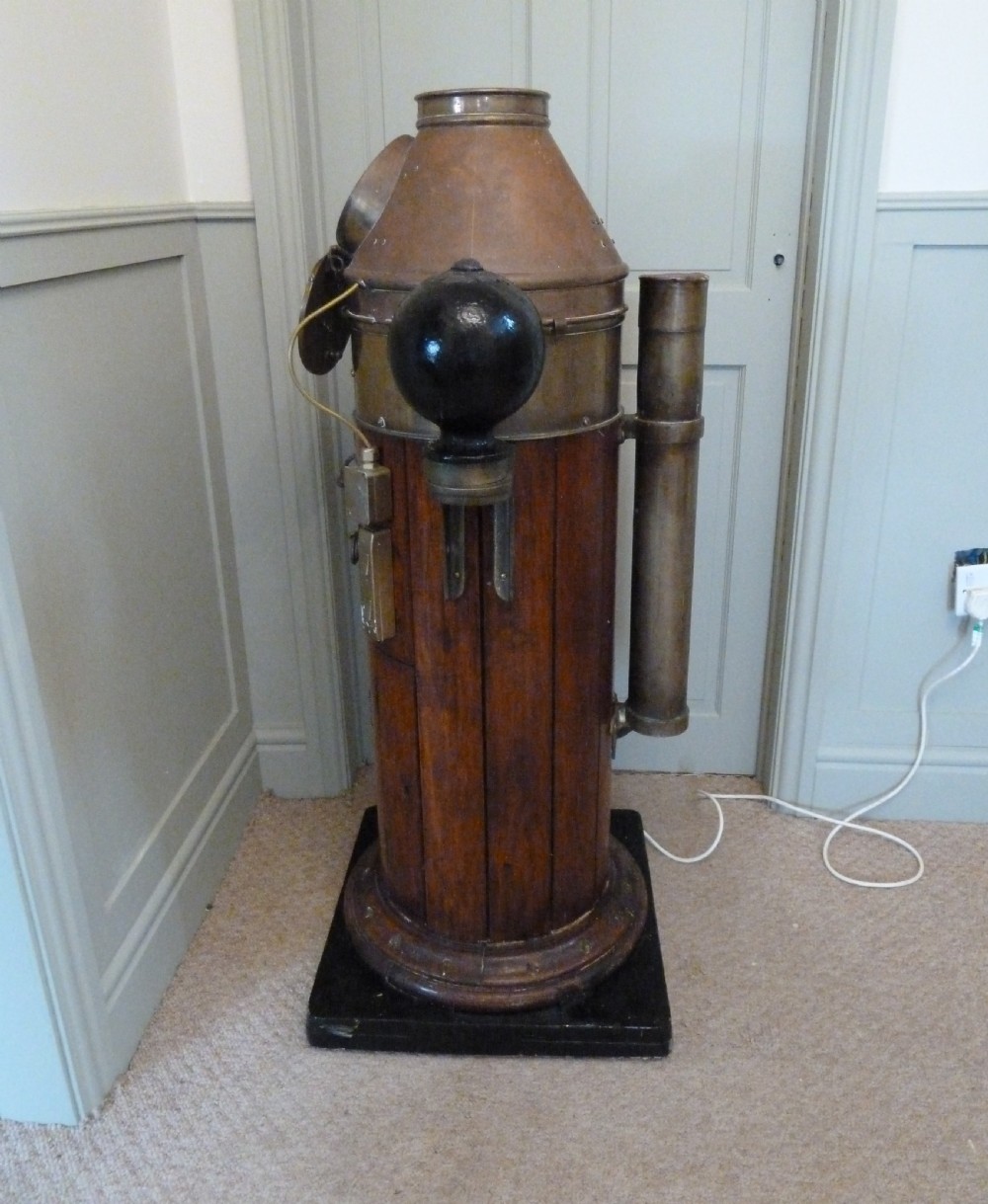 A 19th-century floor-standing ships binnacle featuring a polished brass hood with a glass viewing window, a wooden cylindrical pedestal, and two black iron spheres mounted on side brackets. View XIII