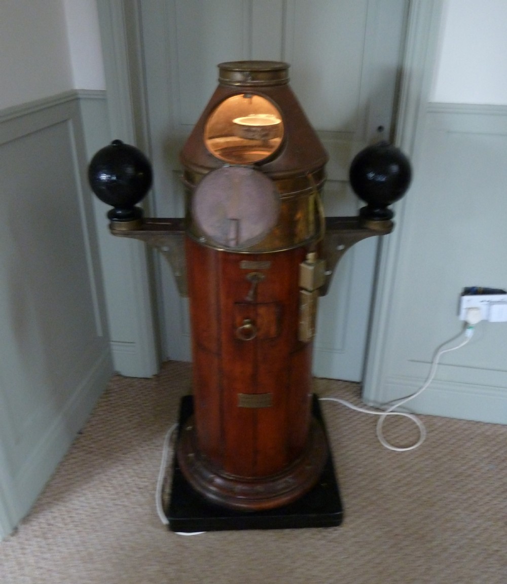 A 19th-century floor-standing ships binnacle featuring a polished brass hood with a glass viewing window, a wooden cylindrical pedestal, and two black iron spheres mounted on side brackets. View XV
