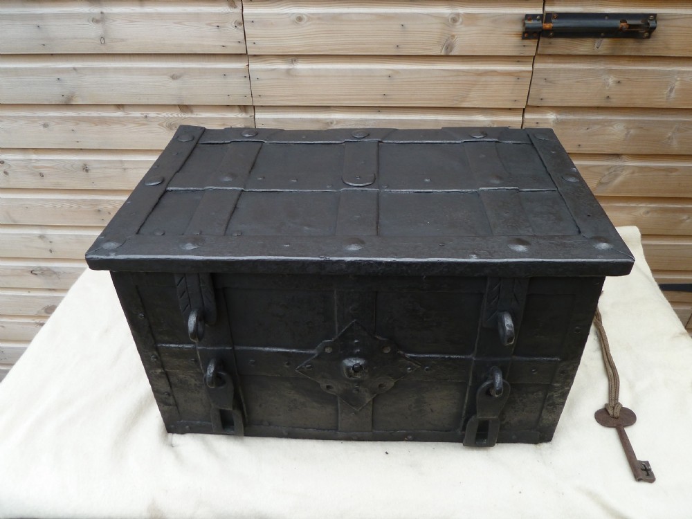 A heavy 17th-century black wrought iron Armada chest with external iron strapwork, side drop handles, and a key sticking out from the top lid. View IV