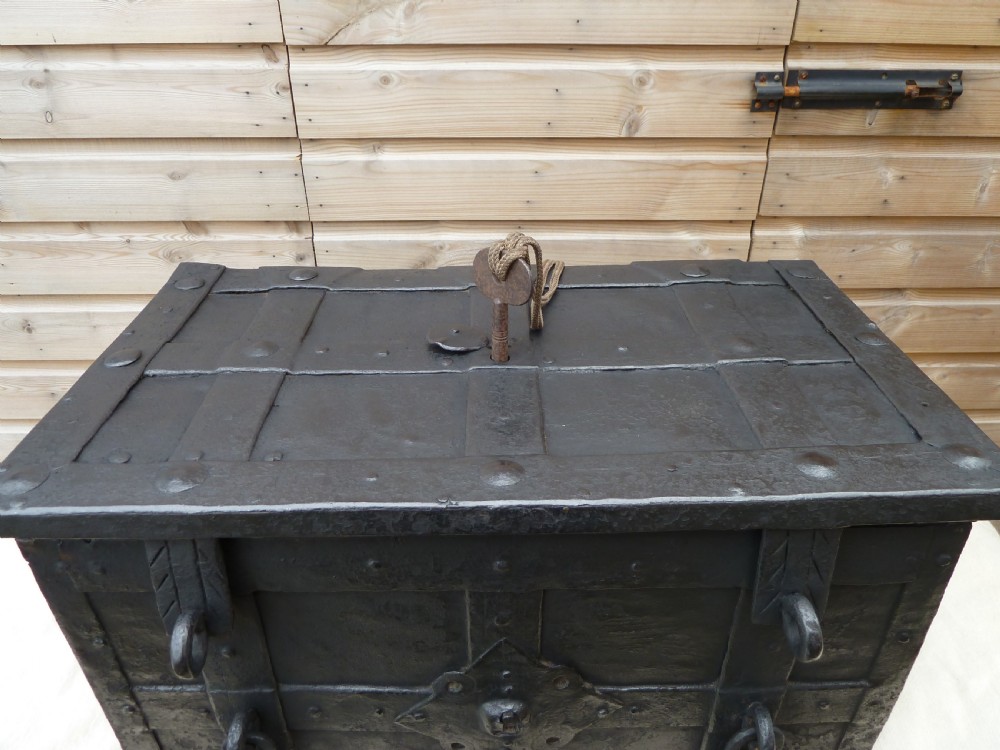 A heavy 17th-century black wrought iron Armada chest with external iron strapwork, side drop handles, and a key sticking out from the top lid. View VI