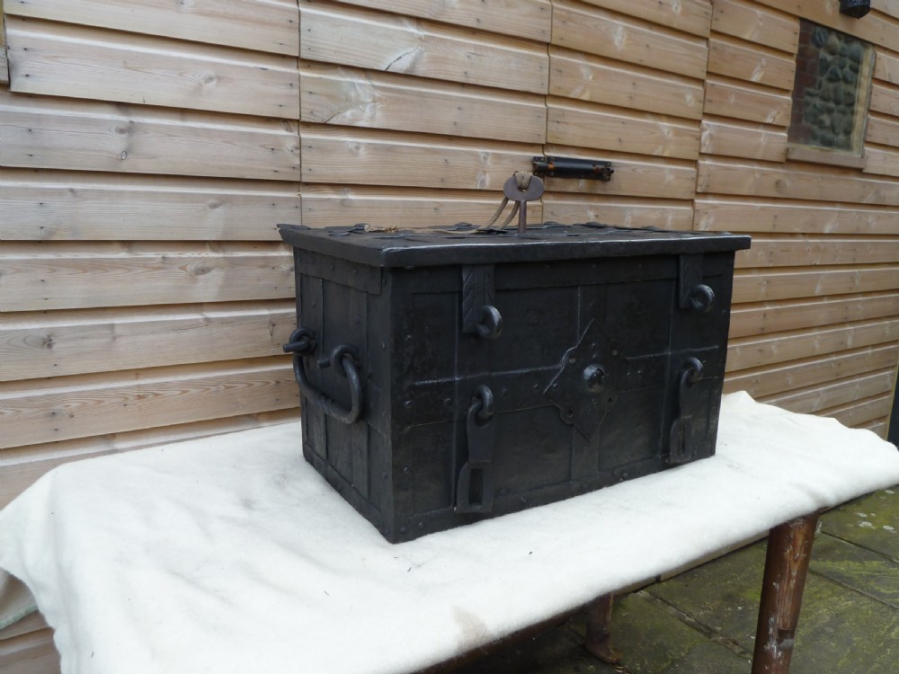 A heavy 17th-century black wrought iron Armada chest with external iron strapwork, side drop handles, and a key sticking out from the top lid. View XVI