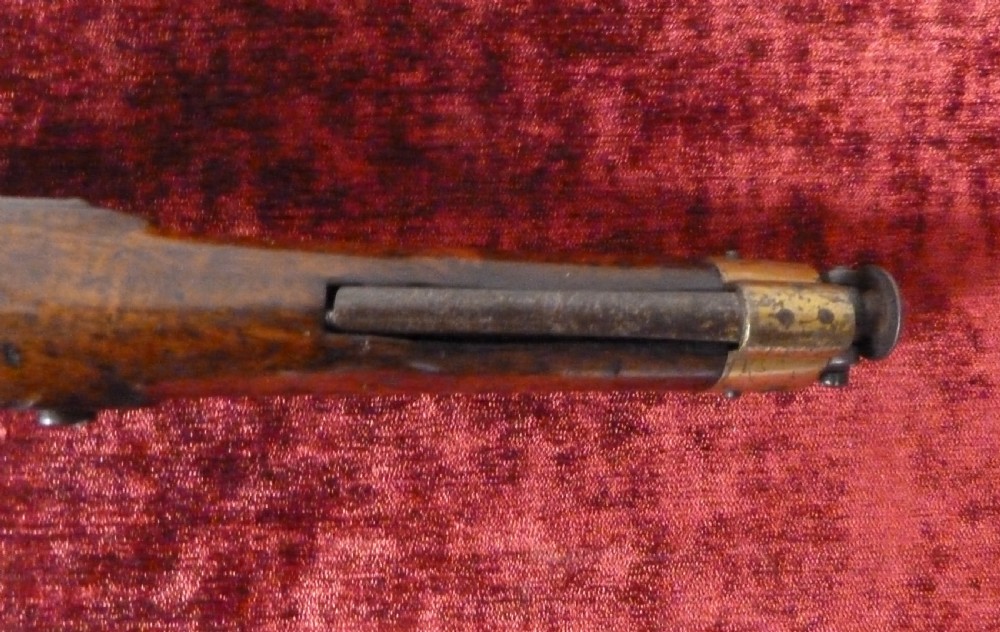 An antique 19th-century East India Company percussion pistol with a dark walnut stock, steel barrel and lock, brass trigger guard, and captive swivel ramrod. View VI