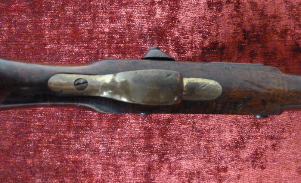 An antique 19th-century East India Company percussion pistol with a dark walnut stock, steel barrel and lock, brass trigger guard, and captive swivel ramrod. View VII