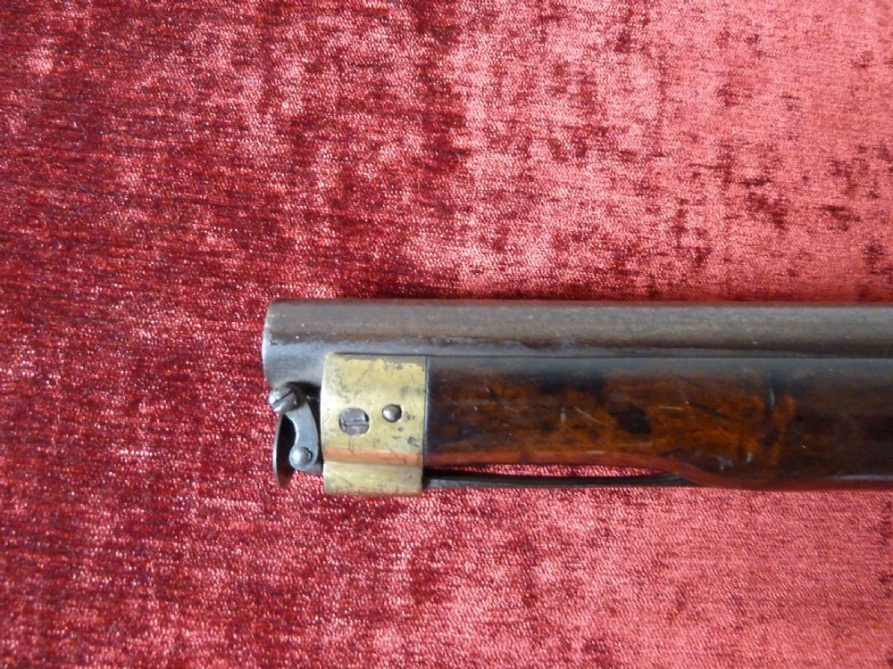 An antique 19th-century East India Company percussion pistol with a dark walnut stock, steel barrel and lock, brass trigger guard, and captive swivel ramrod. View X