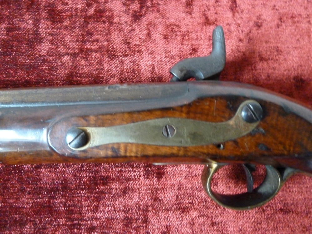 An antique 19th-century East India Company percussion pistol with a dark walnut stock, steel barrel and lock, brass trigger guard, and captive swivel ramrod. View XII
