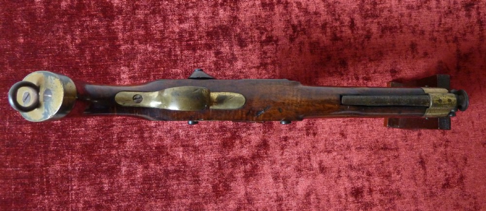 An antique 19th-century East India Company percussion pistol with a dark walnut stock, steel barrel and lock, brass trigger guard, and captive swivel ramrod. View XV