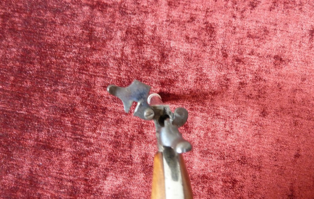 A small 19th-century postmans dog scarer pistol featuring a turned metal barrel, exposed hammer mechanism, and contoured wooden handle. View IV
