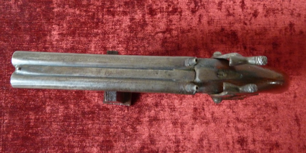 A 19th-century double-barrel percussion pistol featuring side-by-side steel barrels, dual hammers, engraved lockplates, and a smooth walnut stock. View VII