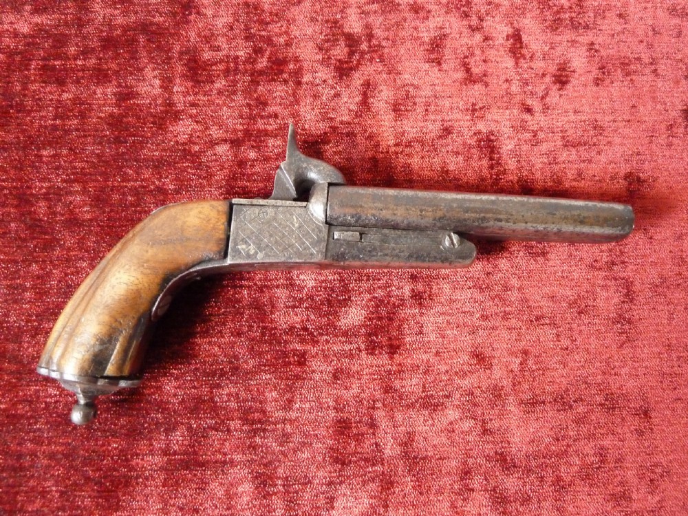 A nineteenth-century double-barrelled rimfire pistol with patinated steel barrels and a contoured wooden grip resting on display stands. View VII