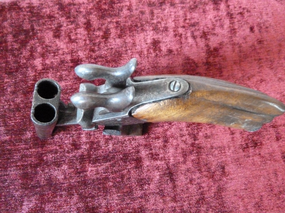 A nineteenth-century double-barrelled rimfire pistol with patinated steel barrels and a contoured wooden grip resting on display stands. View IX