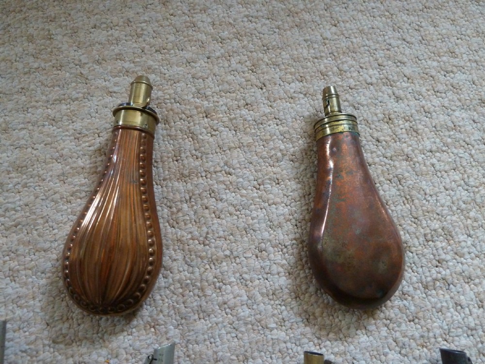 A collection of six 19th-century powder and shot flasks made from embossed copper, brass, and dark brown leather. View II