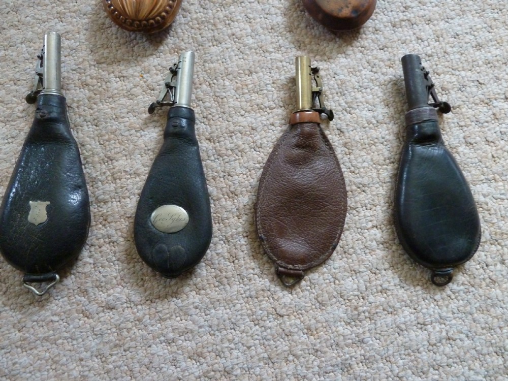 A collection of six 19th-century powder and shot flasks made from embossed copper, brass, and dark brown leather. View III