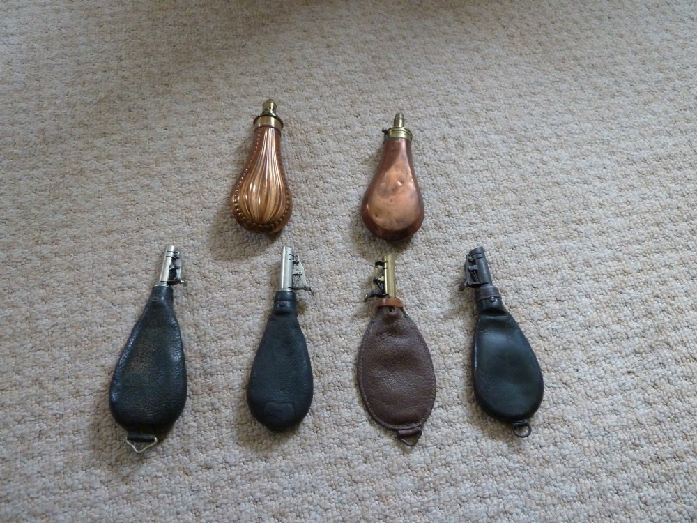 A collection of six 19th-century powder and shot flasks made from embossed copper, brass, and dark brown leather. View IV