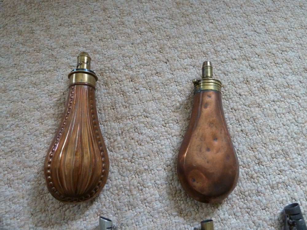 A collection of six 19th-century powder and shot flasks made from embossed copper, brass, and dark brown leather. View V