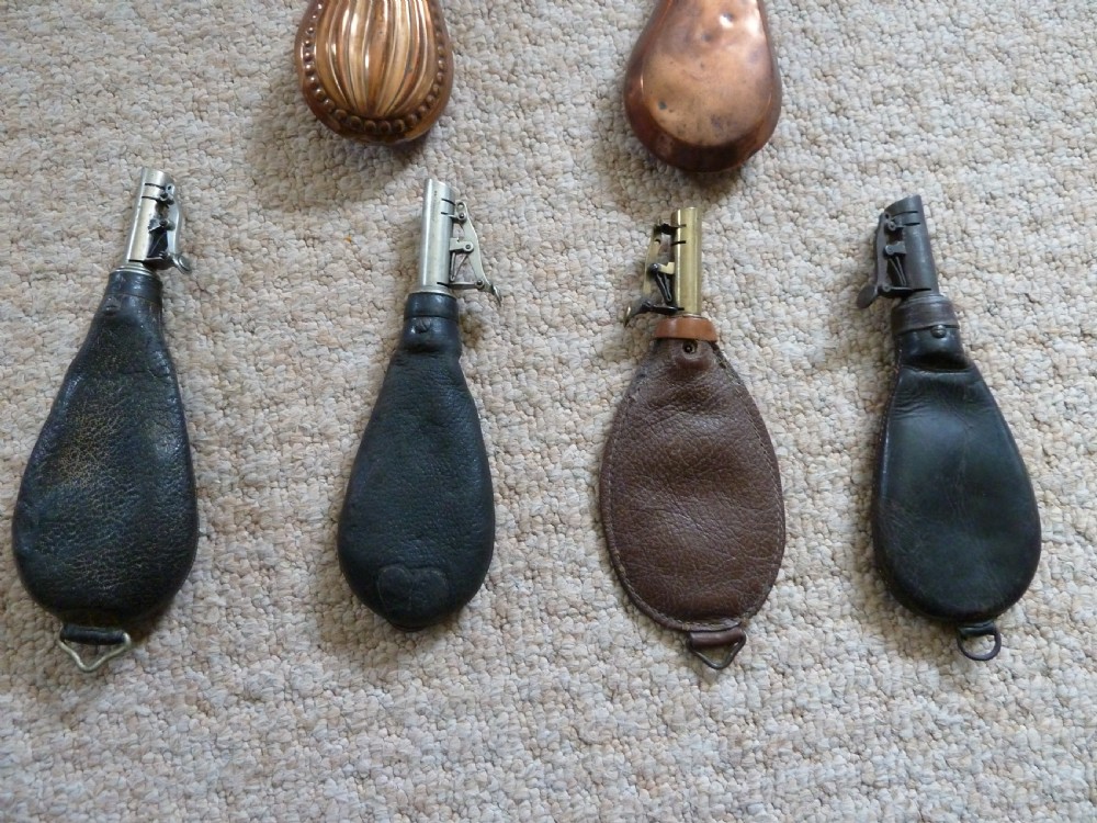 A collection of six 19th-century powder and shot flasks made from embossed copper, brass, and dark brown leather. View VI