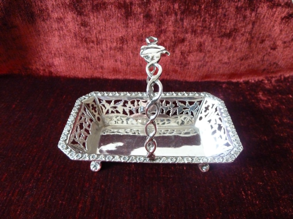An Edwardian rectangular sterling silver basket with pierced fretwork sides, a looped overhead handle, and four cast feet. View VI