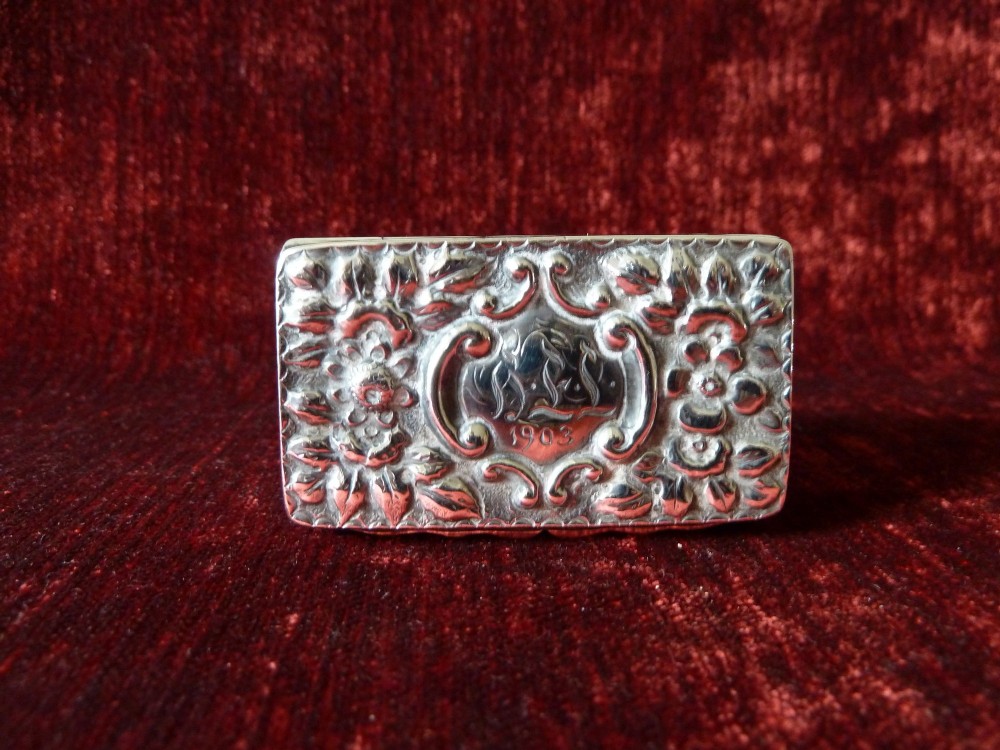 An open rectangular Victorian sterling silver snuff box displaying embossed scrollwork decoration and a gilded interior. View III