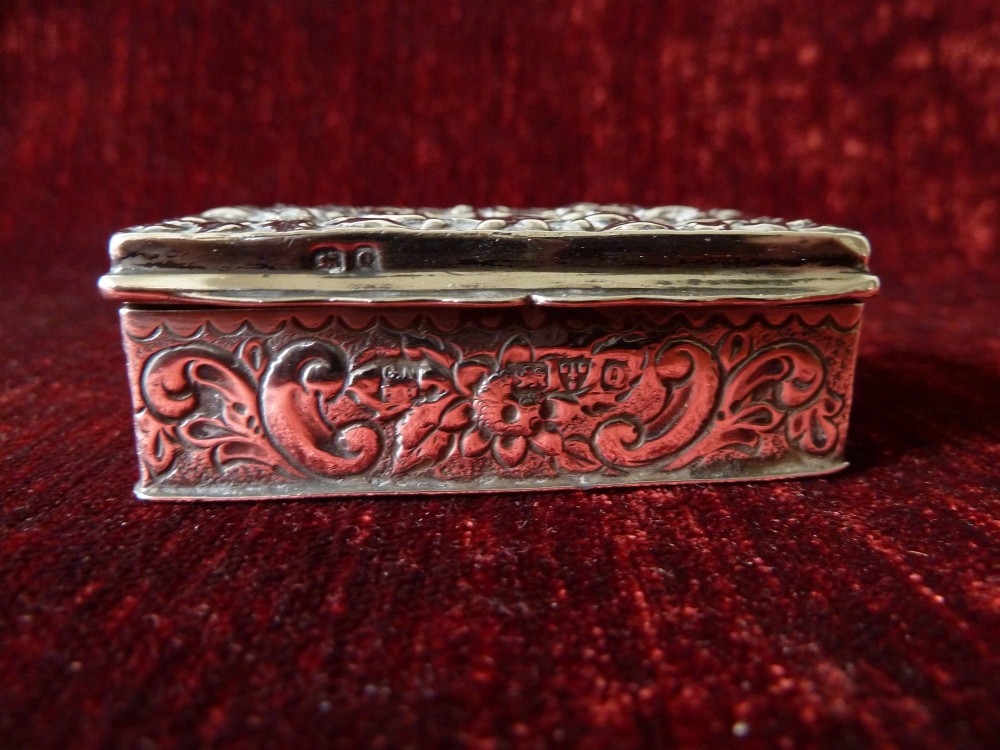 An open rectangular Victorian sterling silver snuff box displaying embossed scrollwork decoration and a gilded interior. View IV
