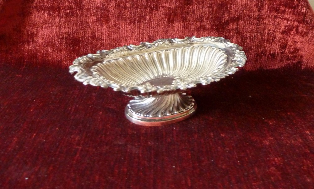 An oval Victorian sterling silver bonbon dish featuring a fluted body, scrollwork rim, and London hallmarks. View II