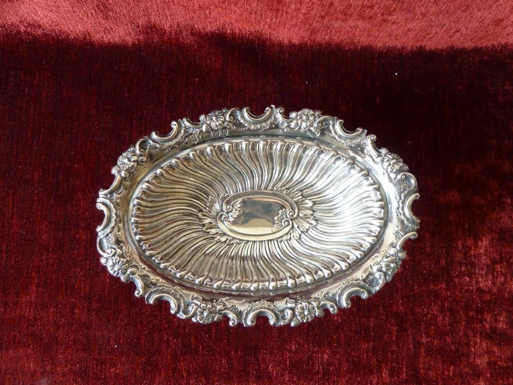 An oval Victorian sterling silver bonbon dish featuring a fluted body, scrollwork rim, and London hallmarks. View III