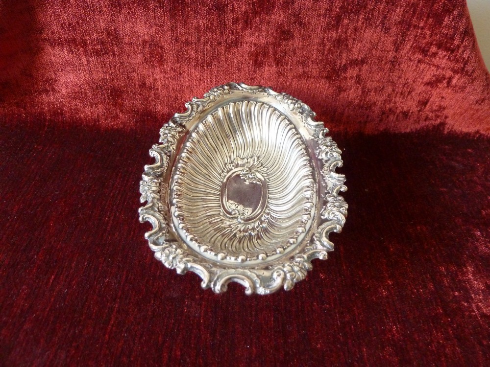 An oval Victorian sterling silver bonbon dish featuring a fluted body, scrollwork rim, and London hallmarks. View IV
