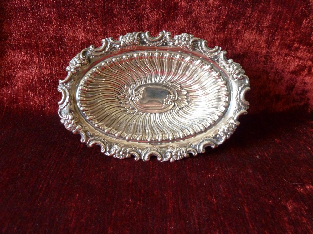 An oval Victorian sterling silver bonbon dish featuring a fluted body, scrollwork rim, and London hallmarks. View VI