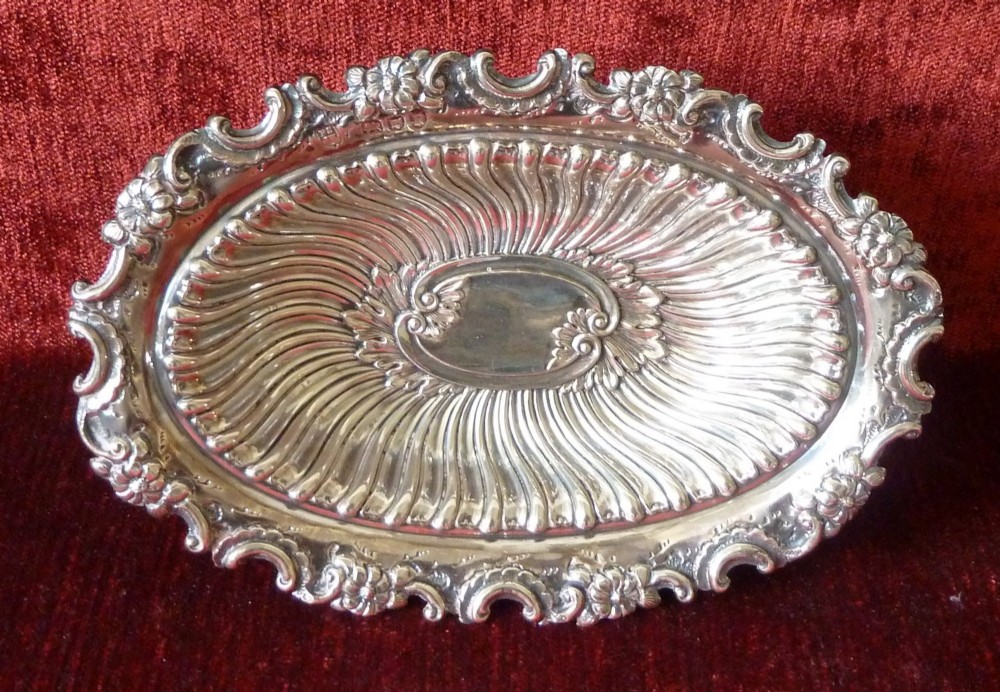 An oval Victorian sterling silver bonbon dish featuring a fluted body, scrollwork rim, and London hallmarks. View VII